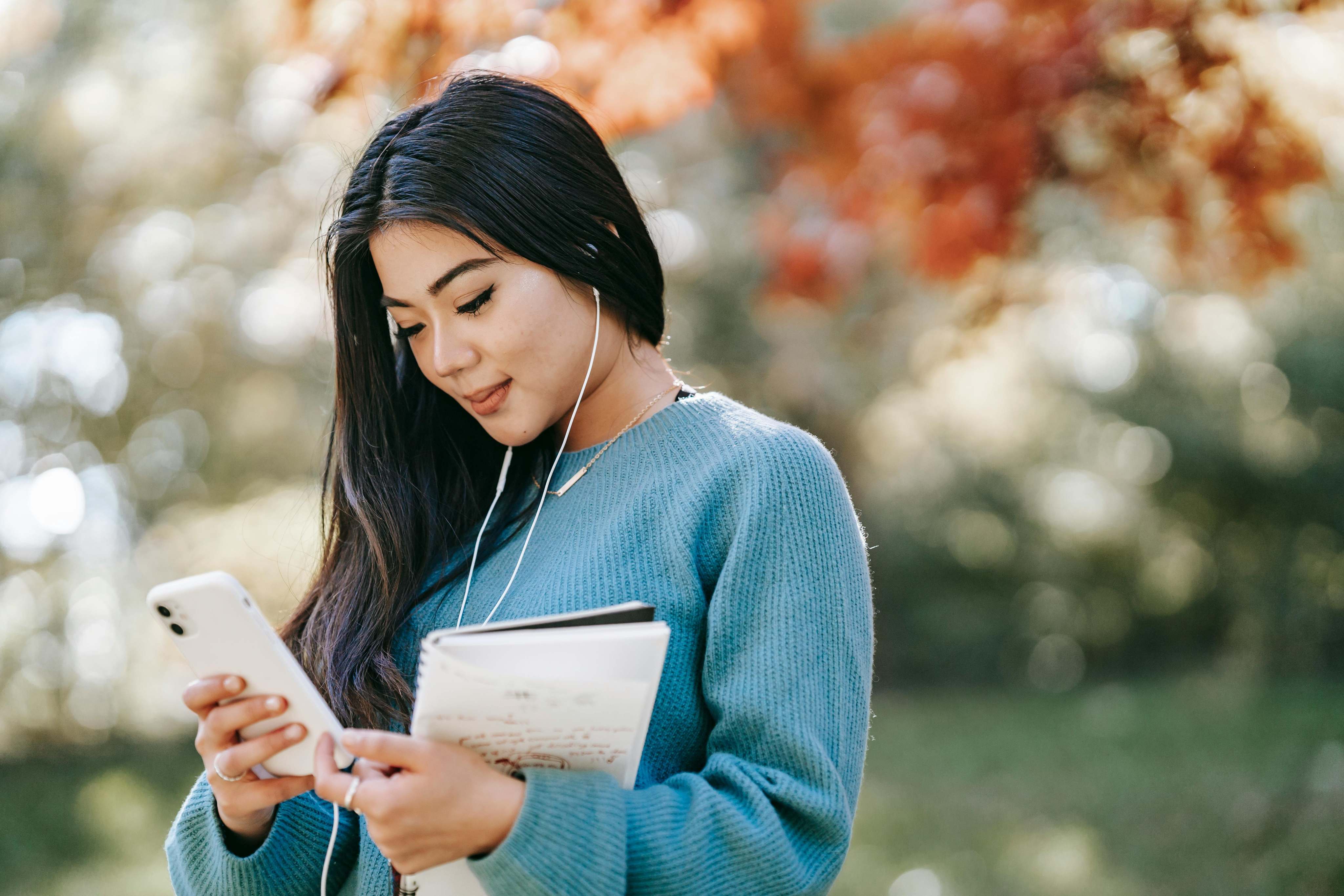 Woman using smartphone and notebook for financial planning